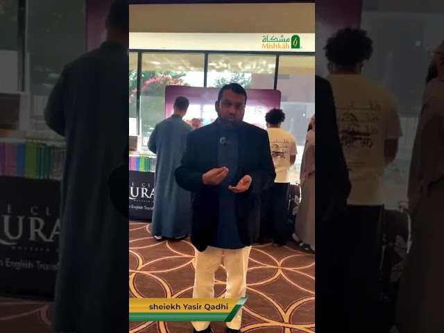 Person using a phone in a public indoor space with others around.